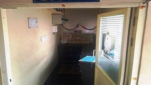 Un pasillo estrecho con un cartel que dice 'OFICINA' sobre una puerta, un escritorio pequeño con una silla y un ventanal con un adhesivo que dice 'BIENVENIDOS'.