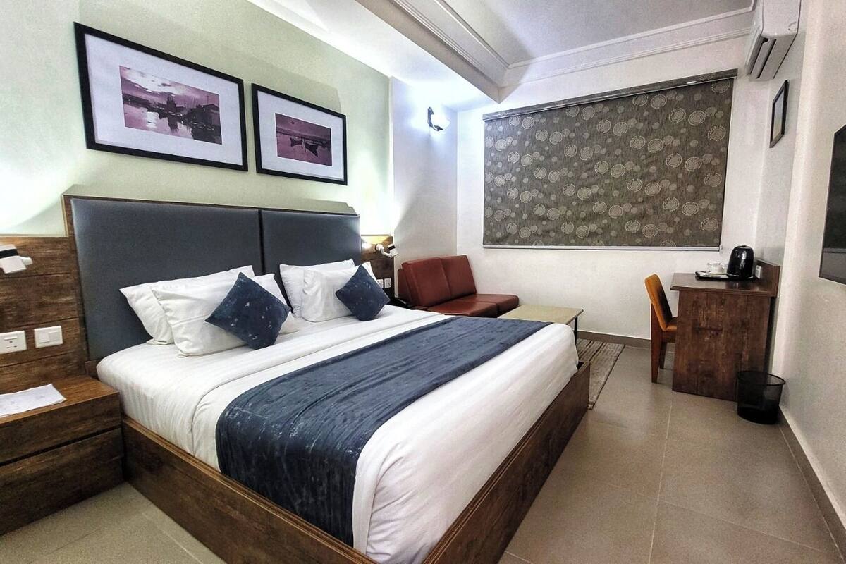 Ein Hotelzimmer mit einem großen Bett, einem Schreibtisch, einem Stuhl und einem an der Wand befestigten Fernseher.