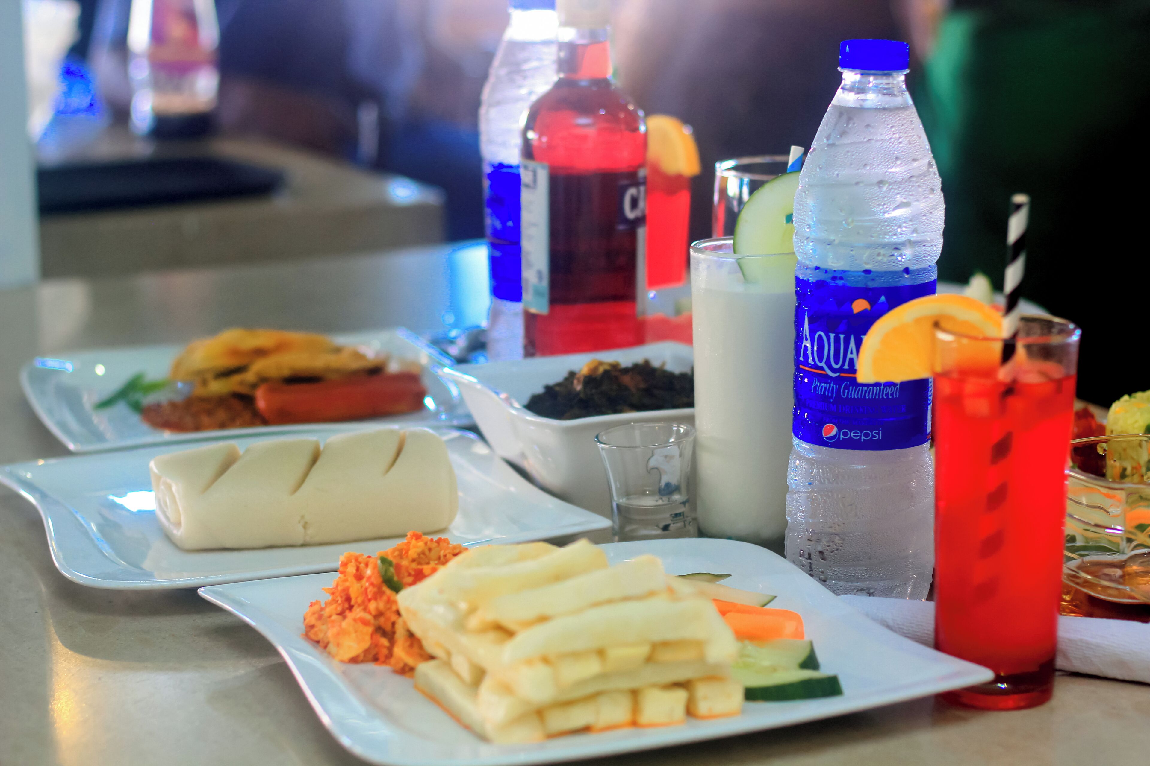 Une table avec différents plats, notamment une assiette de frites, un saladier de salade et un verre d’eau.