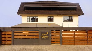 A hotel with a brown roof, a sign reading "Five Clover Hotel," and a wooden fence with horizontal slats. - Five Clover Hotel Monestery Road (Lekki)