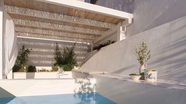 A modern pool area with a clear blue pool, white walls, and a pergola with a woven roof. - Casa boutique Encalada  (Vejer de la Frontera)