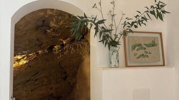 A bathroom with a stone wall, a bathtub, a sink, and a plant.