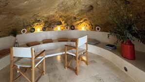A cave-like interior with a wooden bench, a red pot with a plant, and a shelf with decorative items and lights. - Casa boutique Encalada  (Vejer de la Frontera)