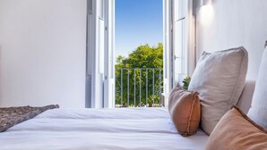 A bedroom with a bed, pillows, and a view of a balcony with a railing and greenery. - Casa boutique Encalada  (Vejer de la Frontera)