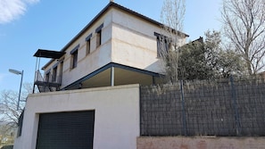 A building with a garage, a balcony, and a metal fence.