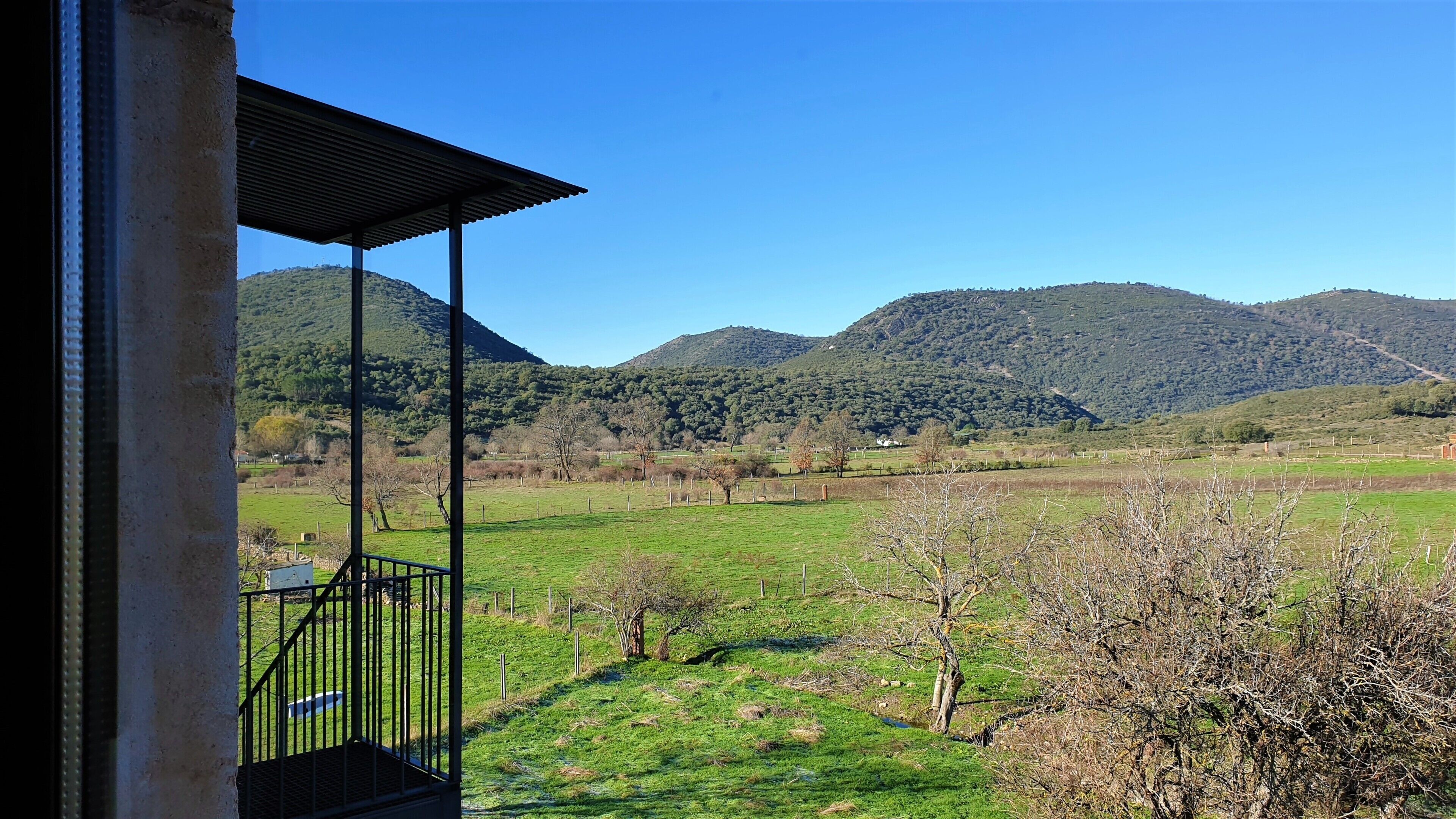 Un balcón con vistas a un campo verde y montañas.