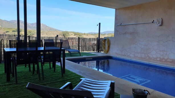 An outdoor pool area with a table and chairs, a hose reel, and a view of distant mountains. - House with private pool in Cabañeros National Park (Navas de Estena)