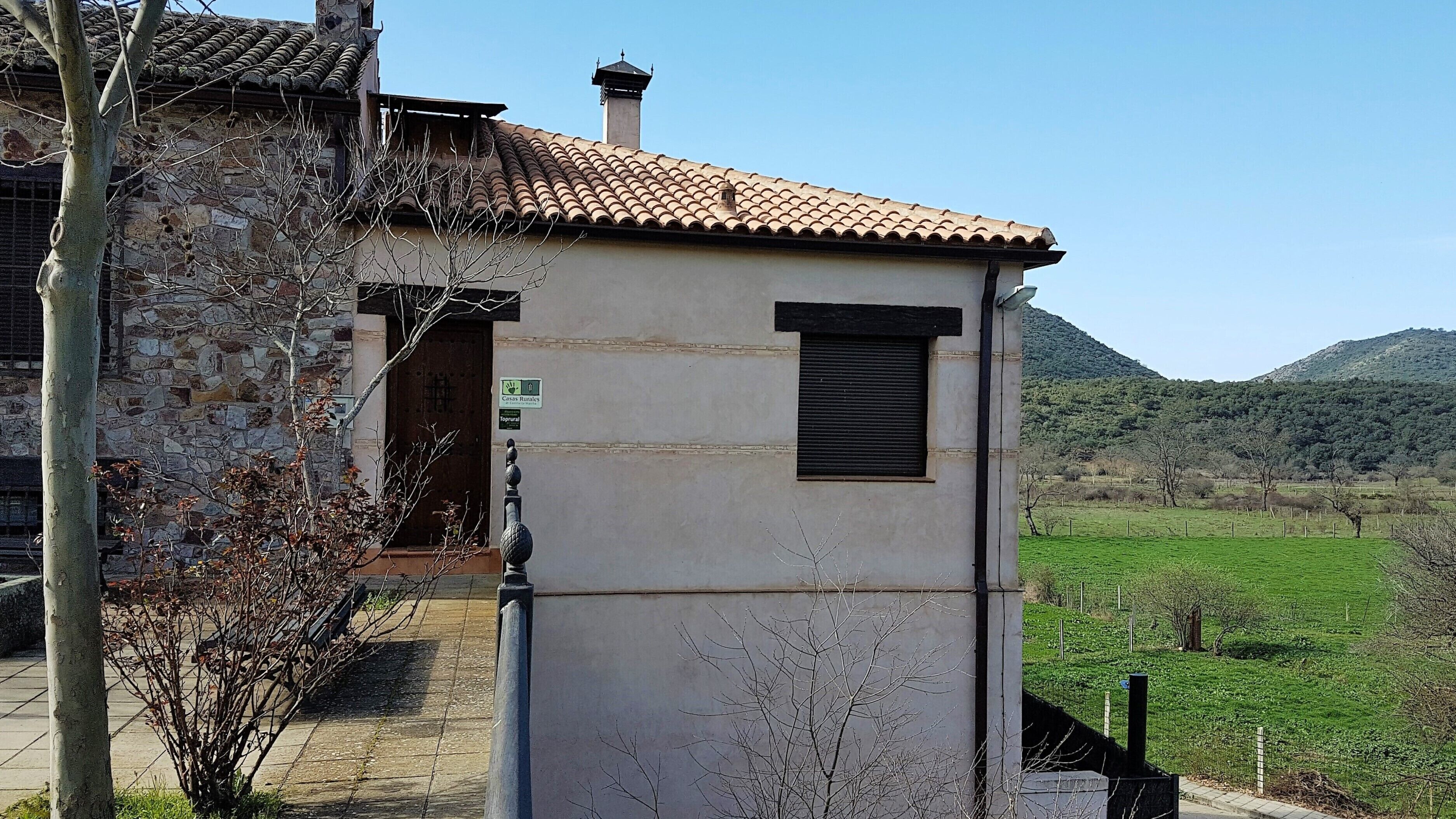 A stone building with a tiled roof, a small window, and a sign indicating a rural setting.