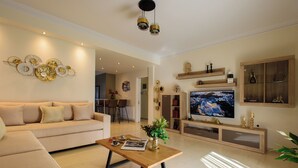 A modern living room with a sofa, coffee table, TV, and decorative wall art. - Blue Ark Harmony Residence (Nea Smirni)