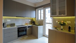 A modern kitchen with grey cabinets, a built-in oven, and a sink. - Blue Ark Harmony Residence (Nea Smirni)