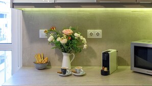 A kitchen with a countertop, a white vase with flowers, a coffee maker, a microwave, and a basket of croissants. - Blue Ark Harmony Residence (Nea Smirni)