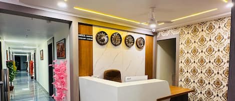 A hotel reception area with a marble floor, a reception desk, and a wall clock.