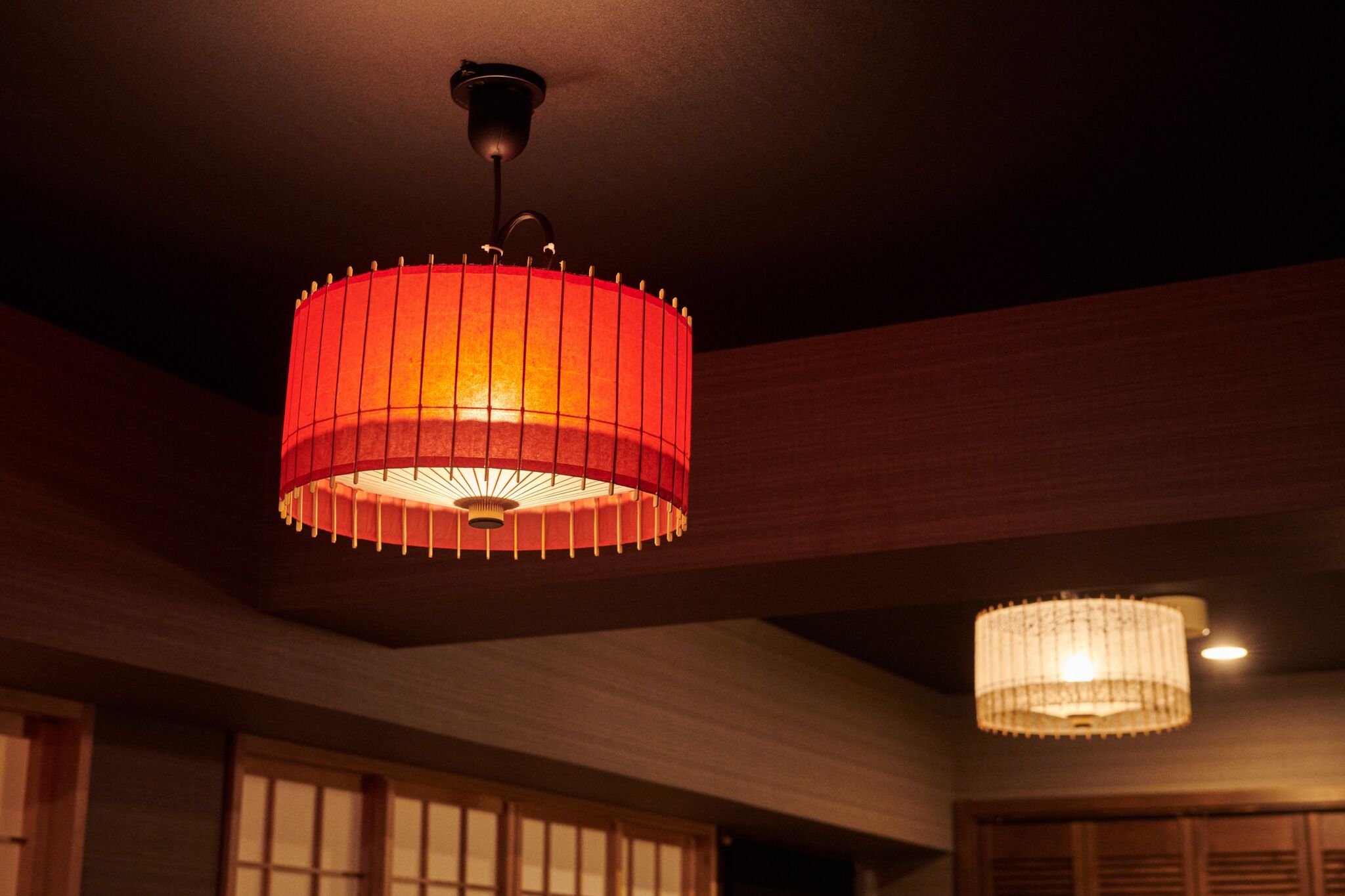 Une pièce dotée d’un luminaire de plafond de style japonais traditionnel et d’une suspension.
