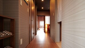 Un pasillo con suelo y paredes de madera que conduce a una habitación con puerta corredera y ventana.