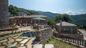 A stone building with outdoor seating and a stone staircase. - Nostos Country House (Zagora-Mouresi)
