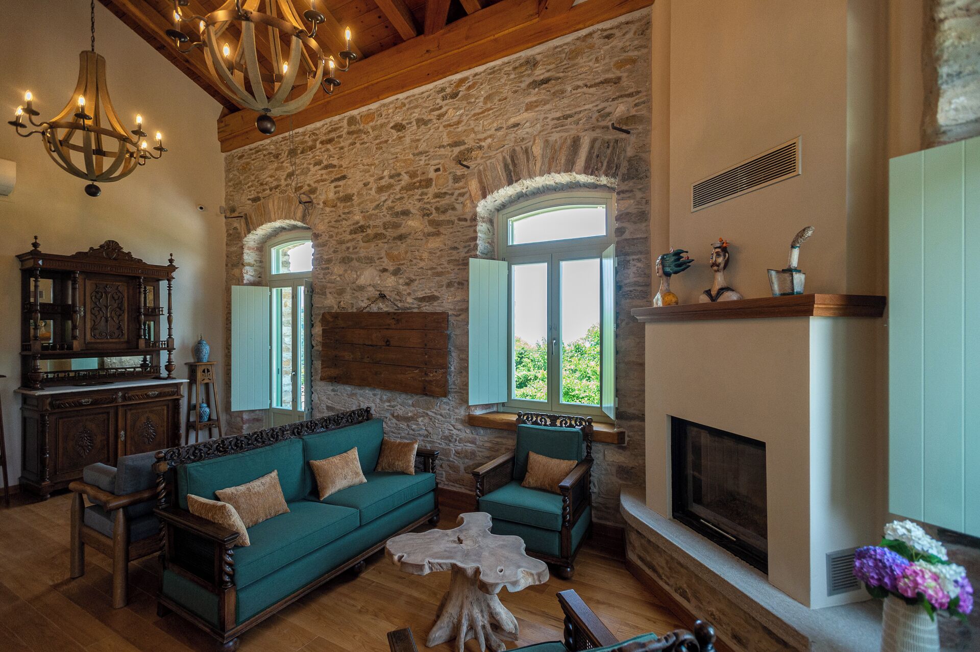 A cozy living room with a stone wall, a fireplace, and a large window.