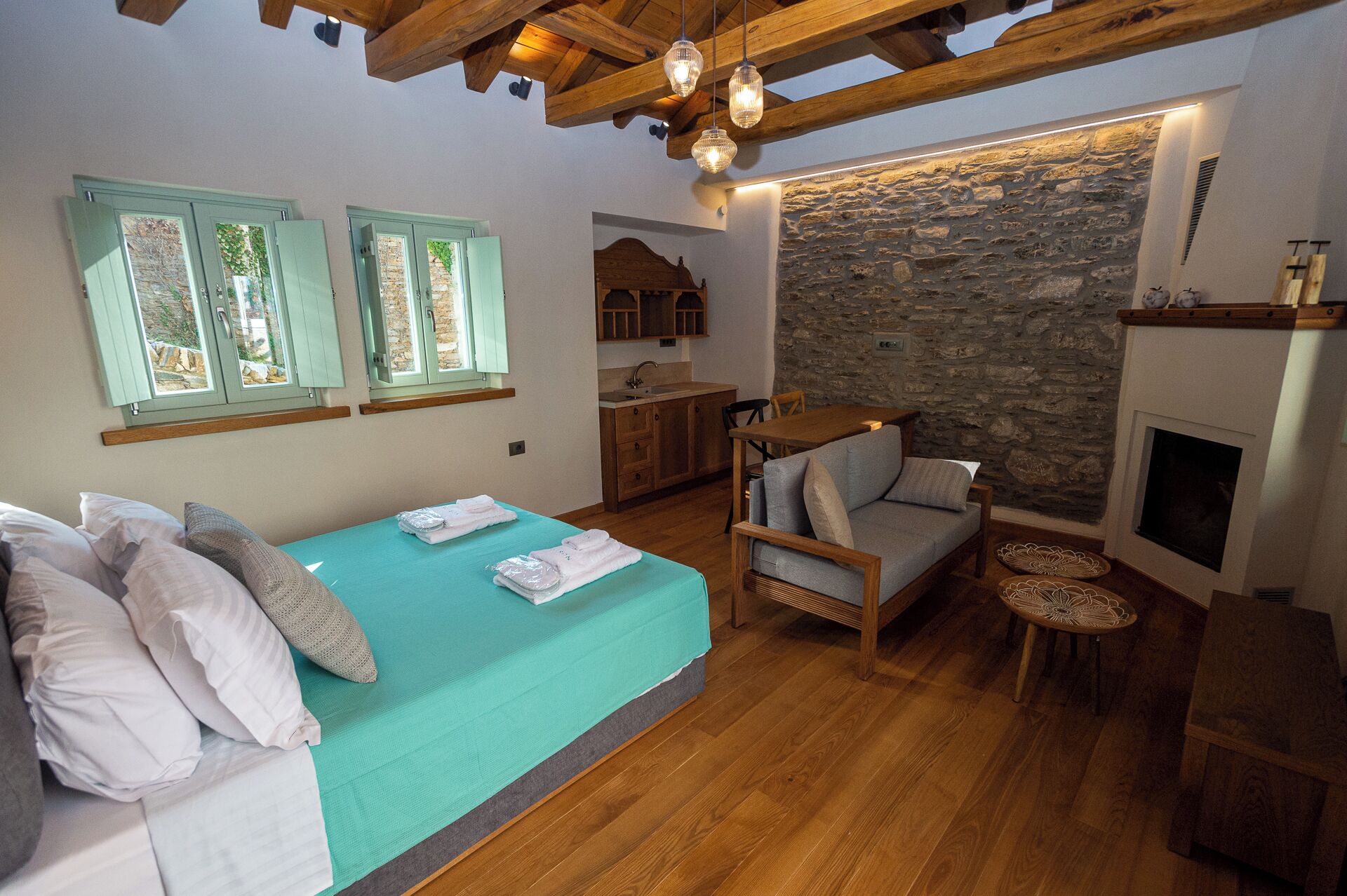 Un dormitorio acogedor con cama, un rincón de descanso, una pared de piedra y chimenea.
