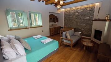 Un dormitorio acogedor con cama, un rincón de descanso, una pared de piedra y chimenea.