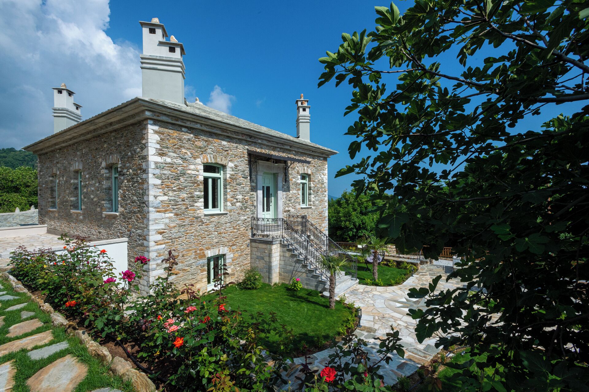A stone building with a balcony and a staircase leading to the entrance.
