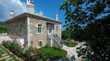 A stone building with a balcony and a staircase leading to the entrance.