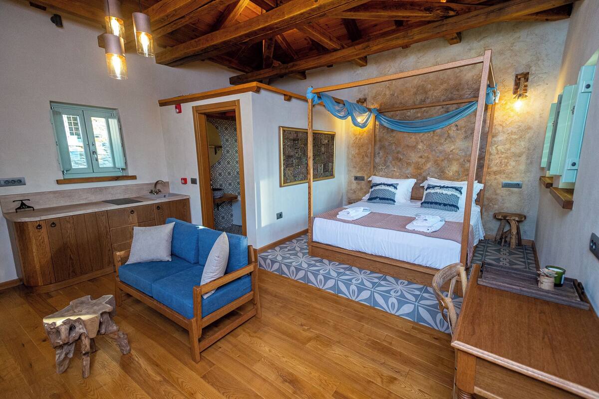 Une chambre à coucher rustique avec un lit à baldaquin, un banc en bois et un petit tabouret.