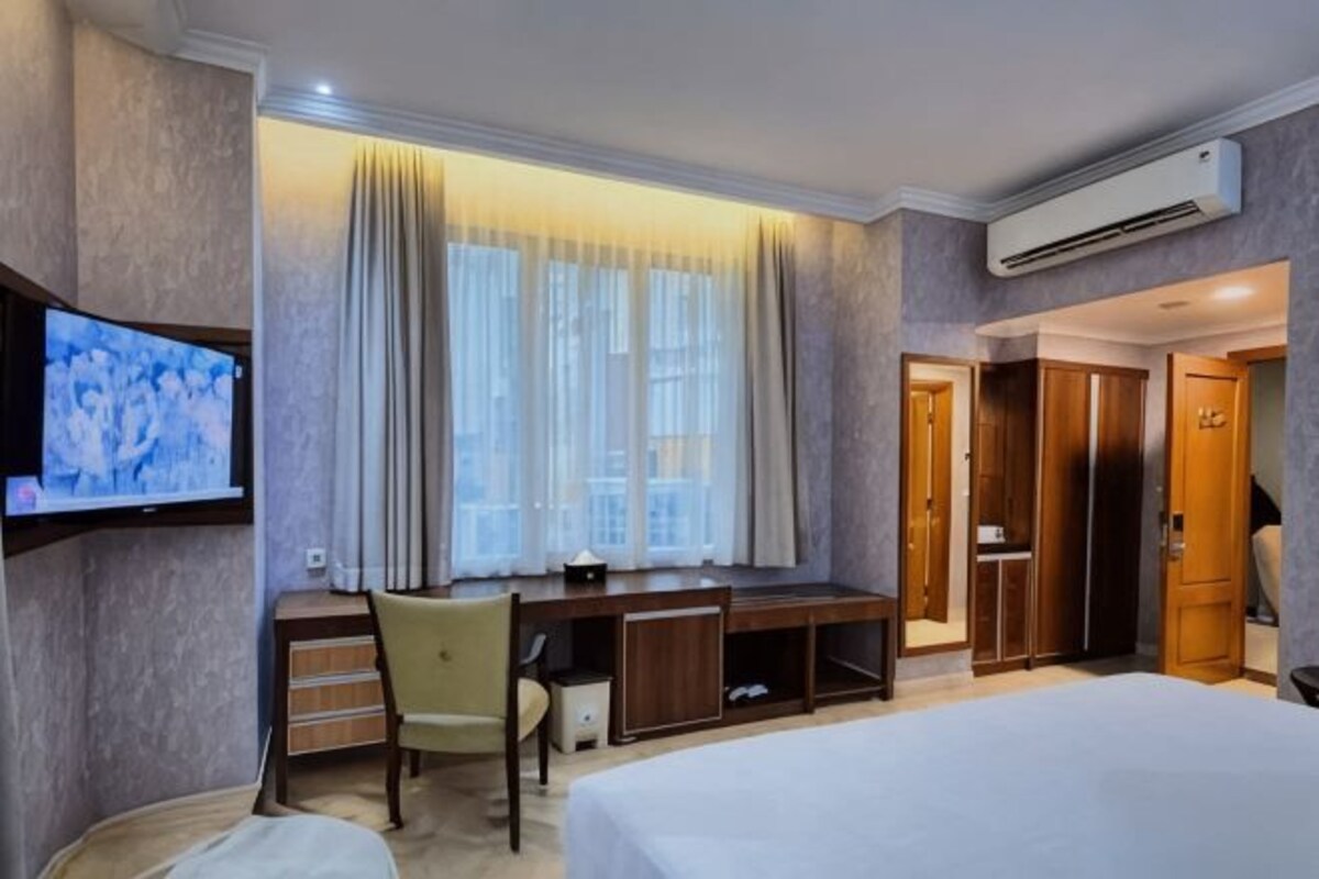 Een hotelkamer met een bed, een bureau, een stoel, een televisie en een kledingkast.