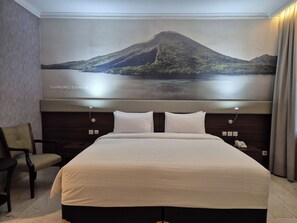 Une chambre d’hôtel avec un grand lit, une chaise, un téléphone et une œuvre d’art fixée au mur représentant une montagne et un lac.