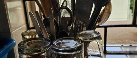 A kitchen utensil holder with various utensils and glass jars.