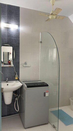 A bathroom with a glass shower enclosure, a sink, and a ceiling fan. - Casa De Abhishek - Breezy 2 BHK (Colva)