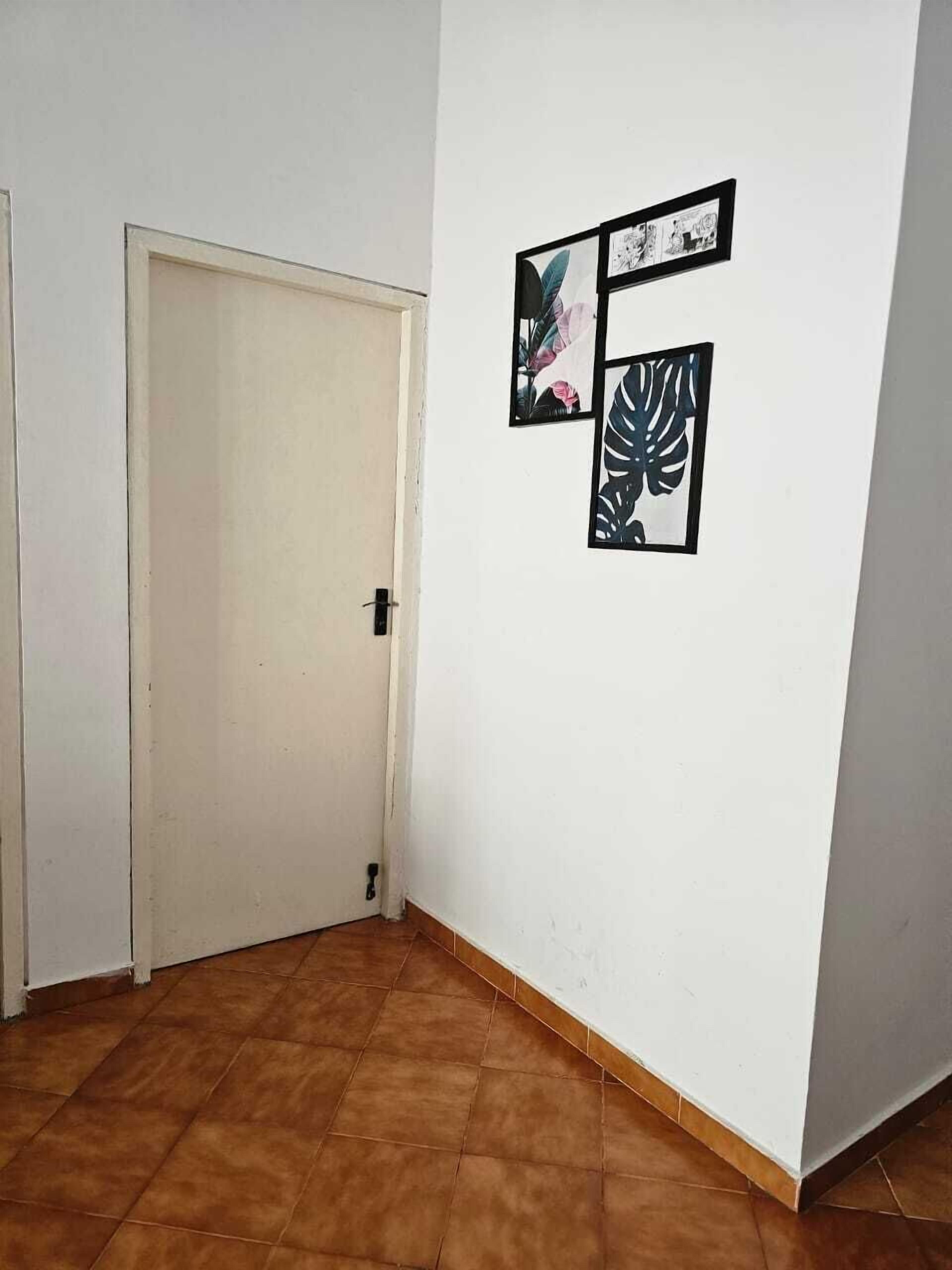 A hallway with a white door and a wall with three framed pictures.