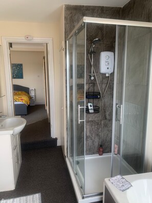 Enjoy a refreshing shower in this bathroom with a glass-enclosed shower area, handheld showerhead, and wall-mounted control panel.