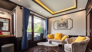 Ein modernes Hotelzimmer mit einer Sofagarnitur, einem runden Couchtisch und einem kleinen Beistelltisch.