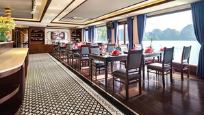 Ein Restaurant mit einer langen Theke, mehreren Tischen und Stühlen, mit Blick auf Wasser und Berge.
