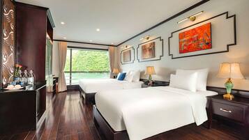 A hotel room with two beds, a large window, and artwork on the walls.