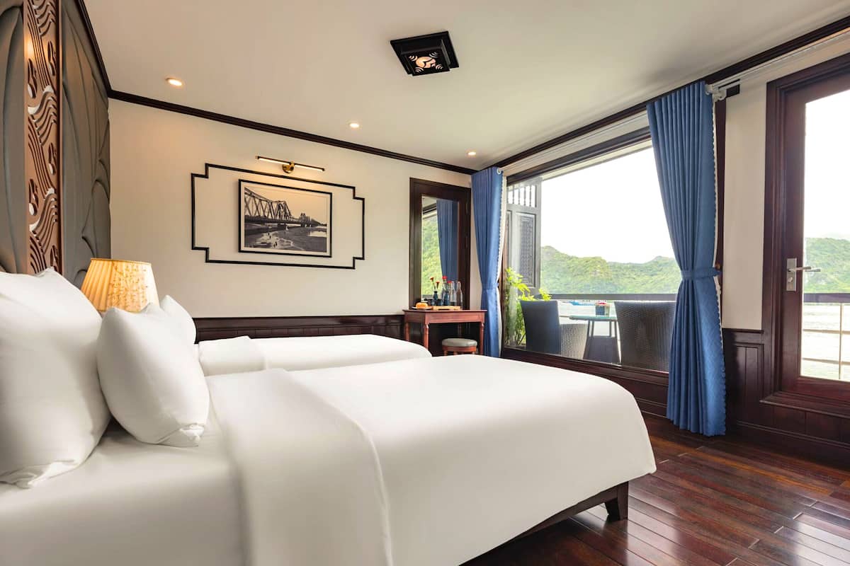 Habitación de hotel con una cama grande, un escritorio con silla, una ventana con cortinas y vista a zonas verdes.