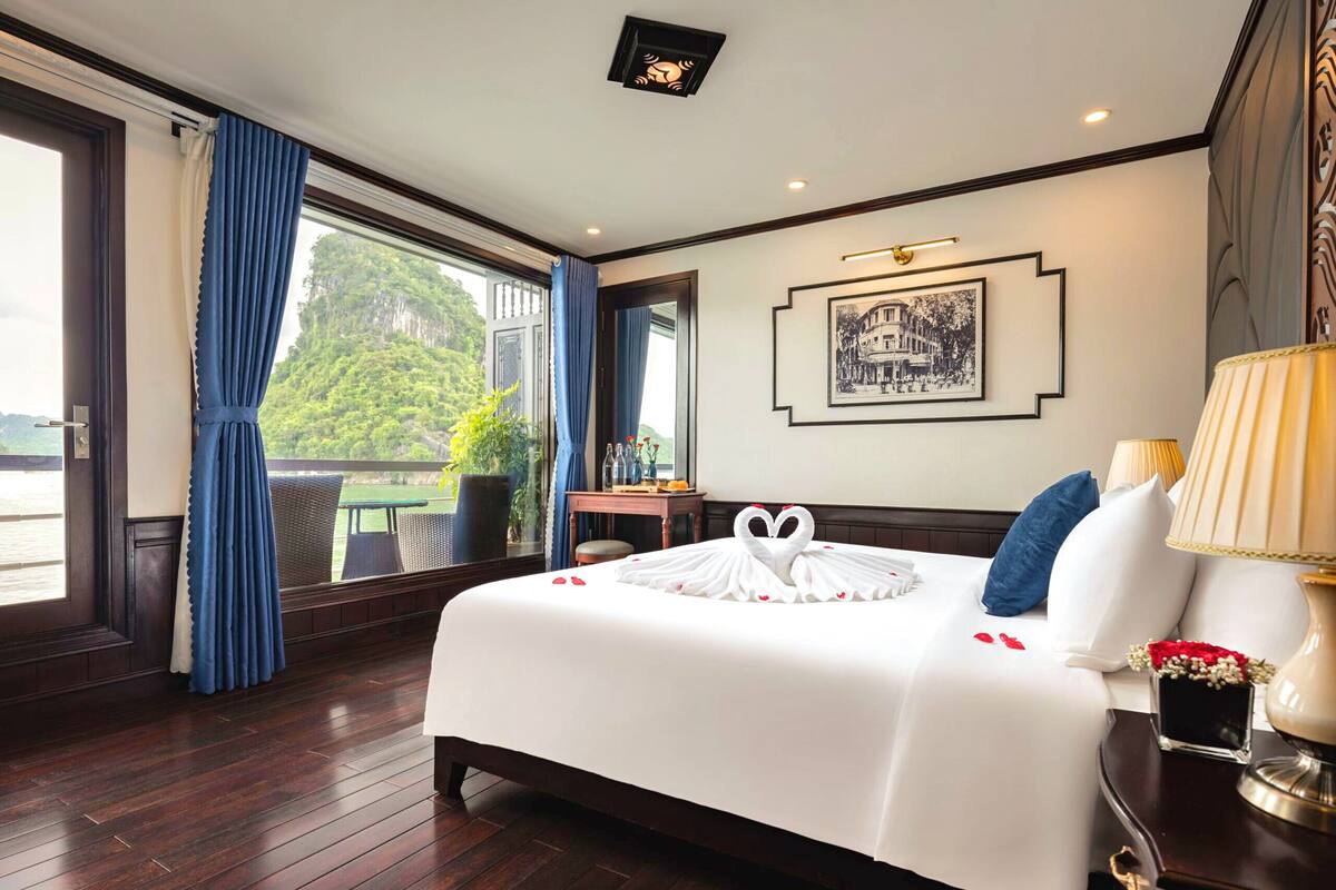 Habitación de hotel con una cama grande, vistas al exterior, un escritorio con una silla y una planta en maceta.