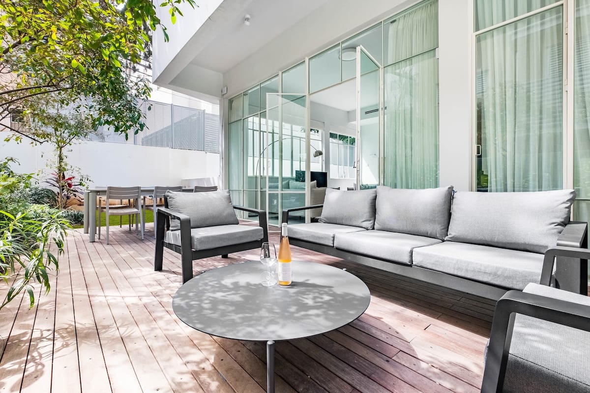 Ein moderner Außenbereich mit rundem Tisch, grauem Sofa und Sesseln.