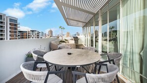 A rooftop terrace with a round table and wicker chairs, overlooking a cityscape.