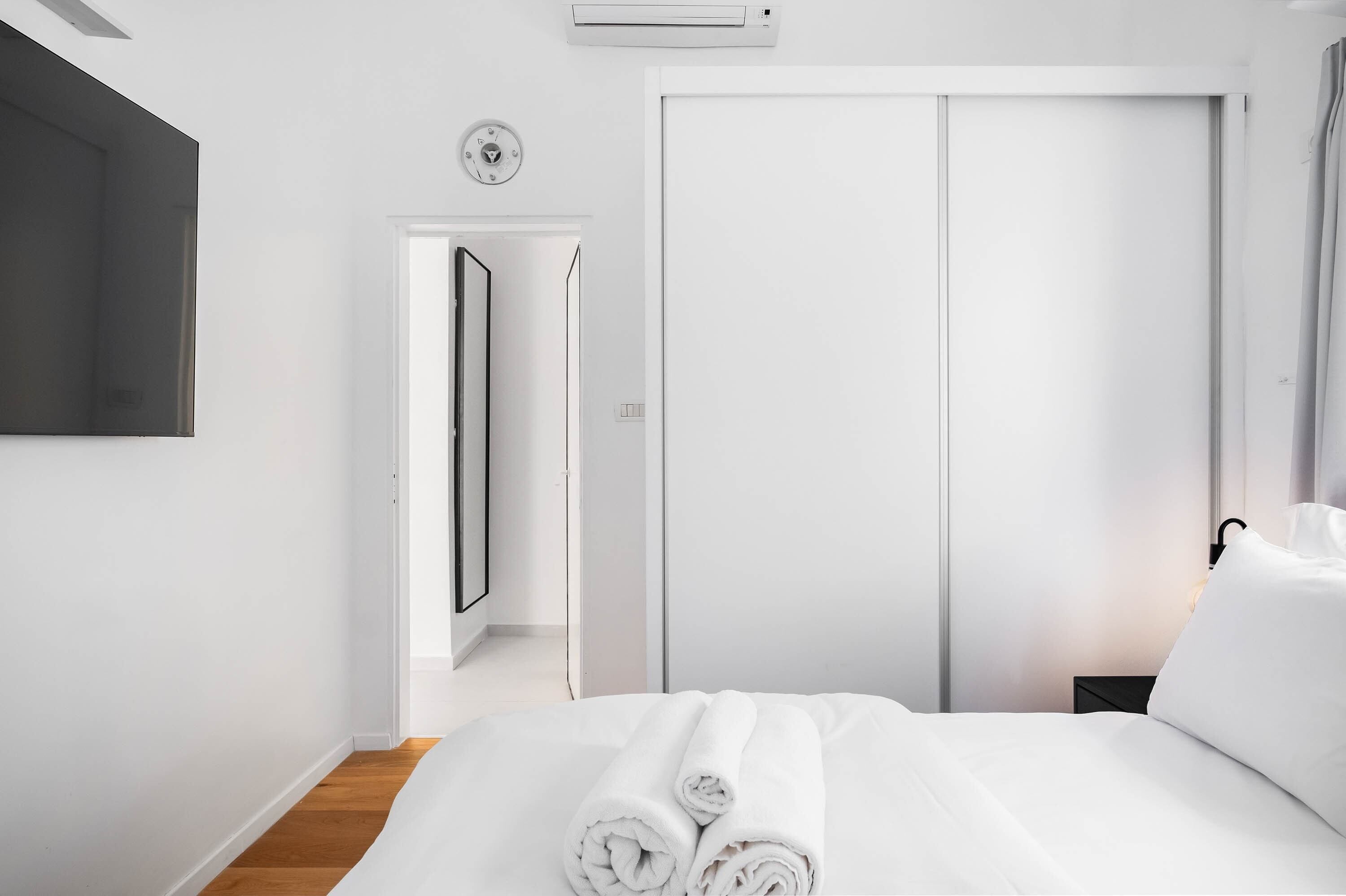 Une chambre d’hôtel avec un lit, une armoire, un miroir et une horloge au mur.