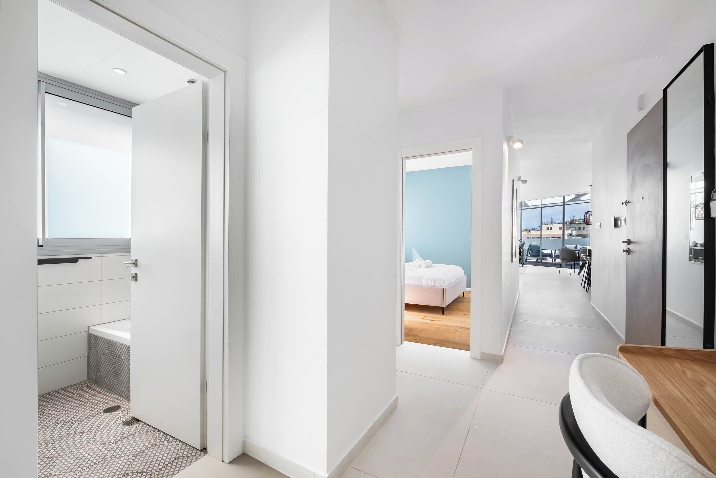 Moderni hotellikäytävä, jossa on kylpyhuone, makuuhuone ja ruokailutila.