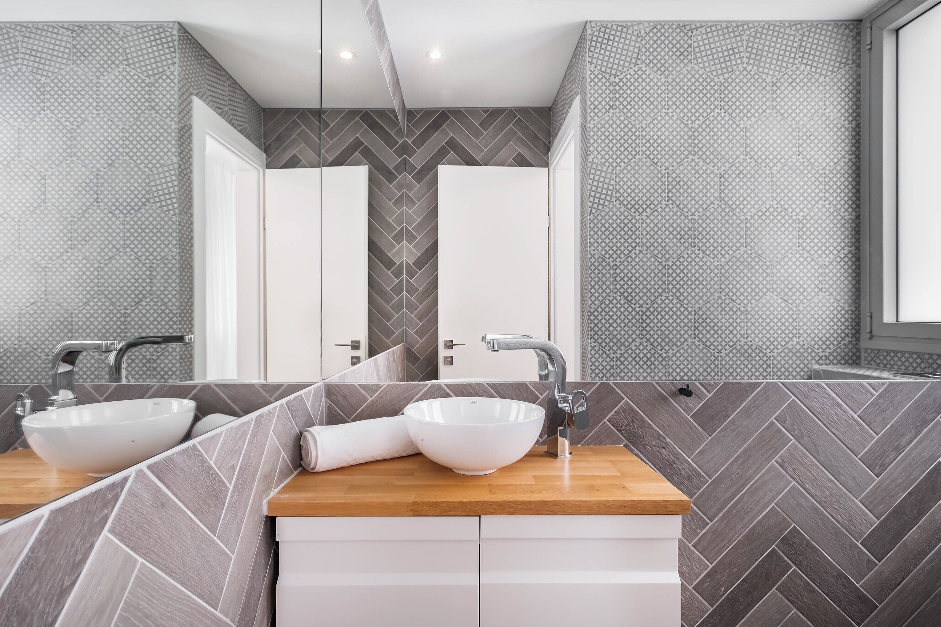 A modern bathroom with two sinks, a wooden countertop, and a mirror.