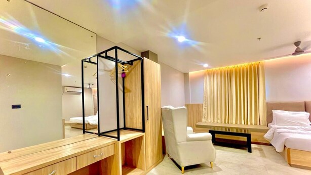 Una habitación de hotel moderna con escritorio de madera, una silla, una cama, un espejo y una ventana con cortinas.