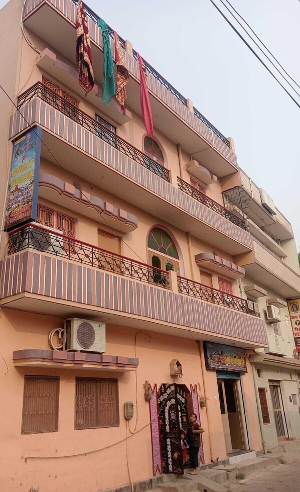 A multi-story building with balconies, a sign for a guest house, and an air conditioning unit.