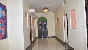 A hallway with a chandelier, a door with a green arch, and a poster on the wall. - Rudra Guest House (Varanasi)