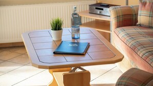 Una mesa pequeña con una computadora portátil, una botella de agua y una planta en maceta.
