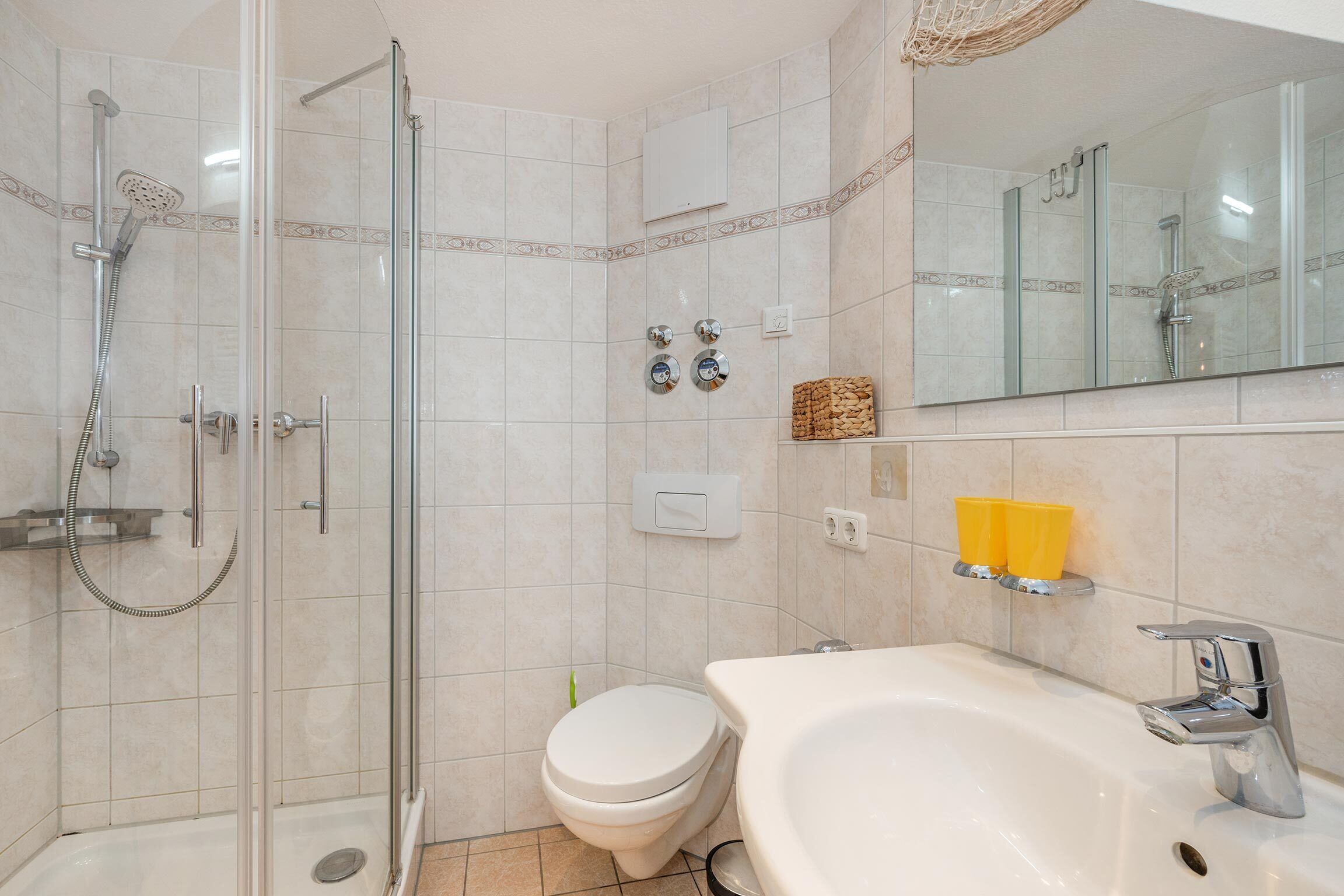A bathroom with a glass-enclosed shower, a toilet, and a sink with a mirror above it.