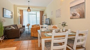 Un salon confortable avec un canapé, une table à manger et des chaises, un téléviseur et un tableau accroché au mur.