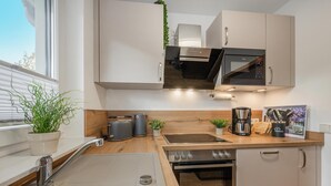 Eine moderne Küche mit weißen Schränken, einer Edelstahl-Spüle, einem eingebauten Backofen, einer Mikrowelle und einer Holz Arbeitsplatte.