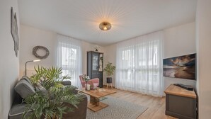 Ein modernes Wohnzimmer mit Sofa, Couchtisch und Fernseher auf einem Schrank.
