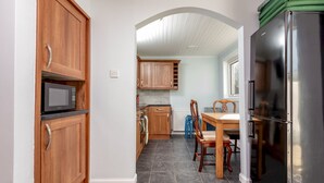 Una cucina con mobili in legno, un frigorifero in acciaio inossidabile, un forno a microonde e un'area pranzo con tavolo e sedie.